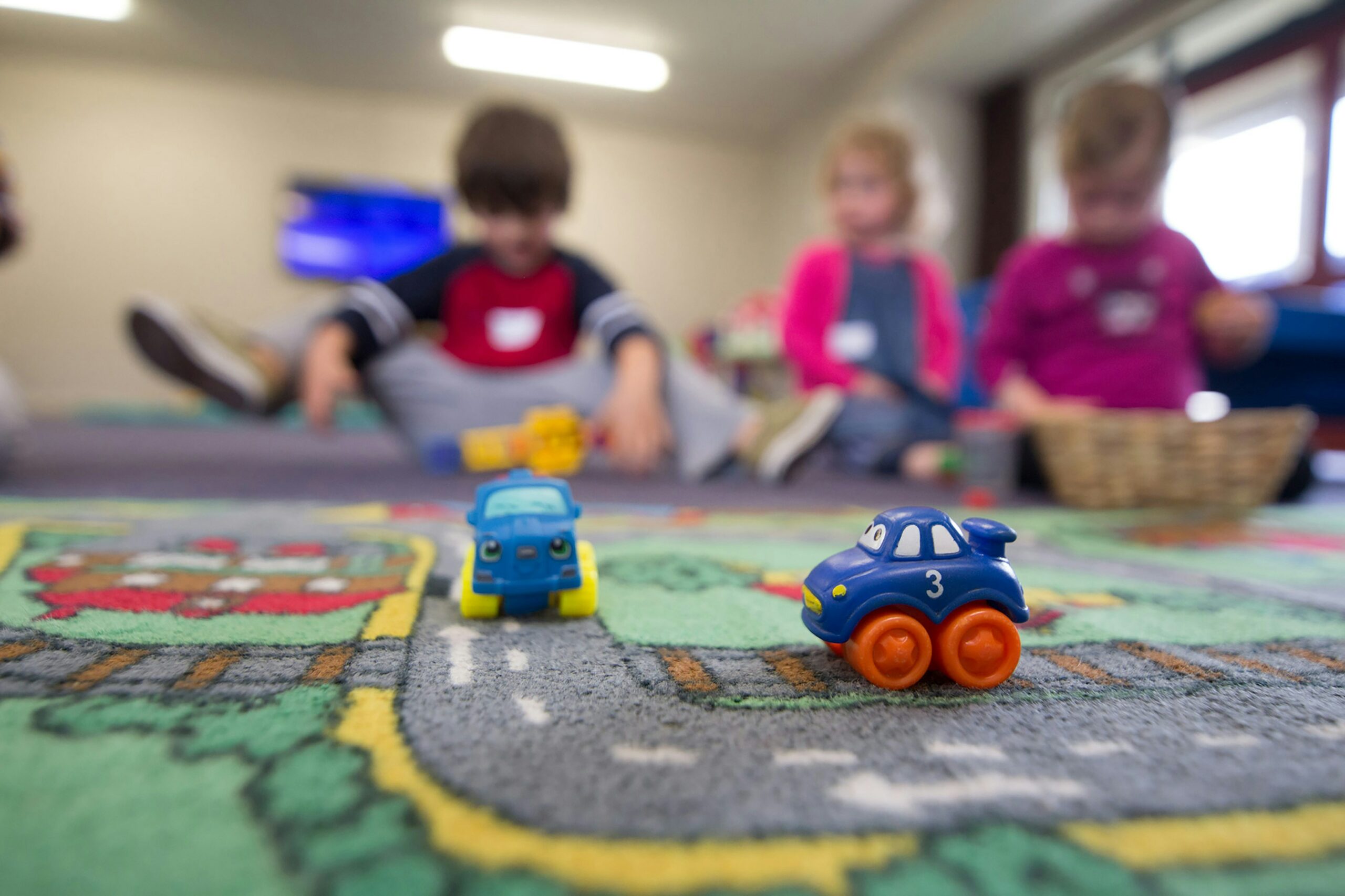kids playing on a mat with toy cars